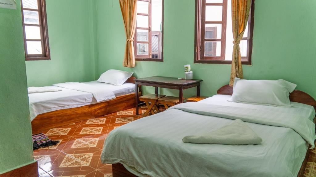 琅勃拉邦Mao Pha Sok Guesthouse的配有两张床铺的绿色墙壁和窗户