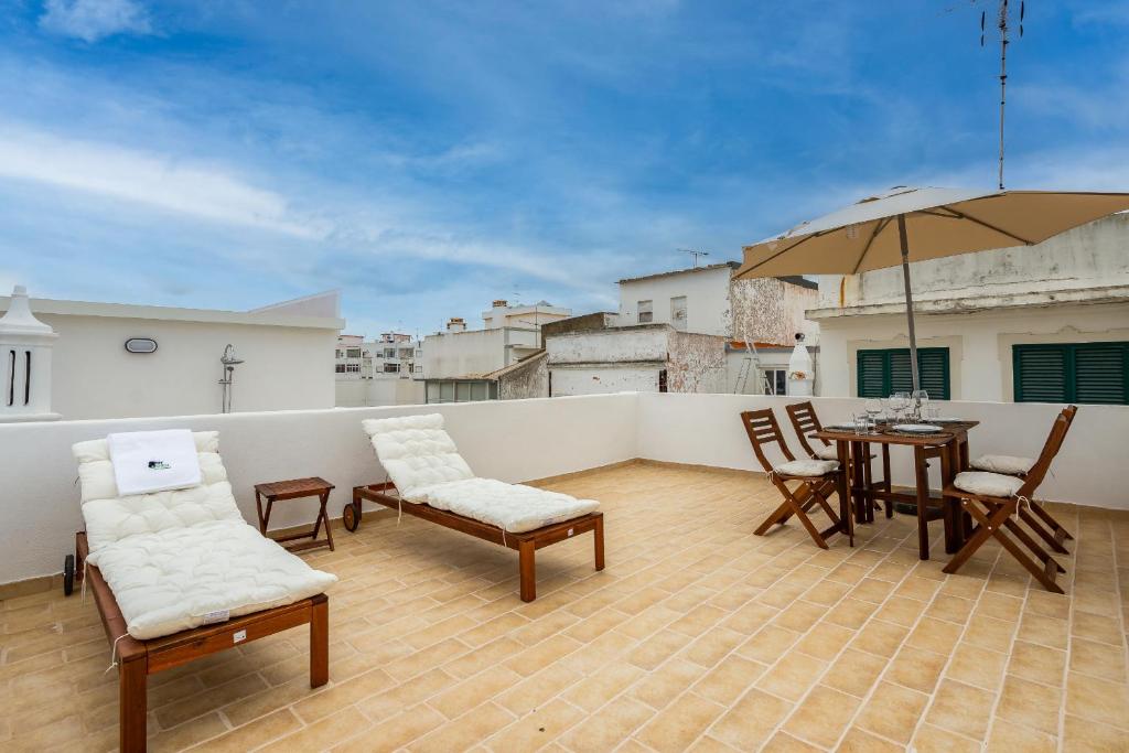 夫塞塔Tia Anica House II - apartment with terrace in central Fuseta beach village的阳台配有桌椅和遮阳伞。