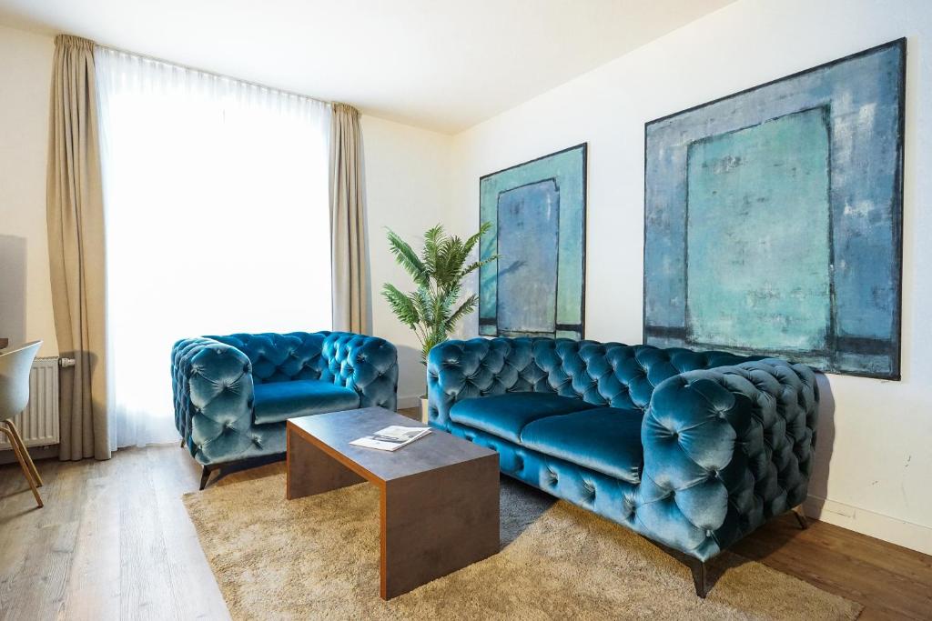 劳茵戈恩卡奈凯勒酒店的客厅配有2张蓝色的沙发和1张桌子