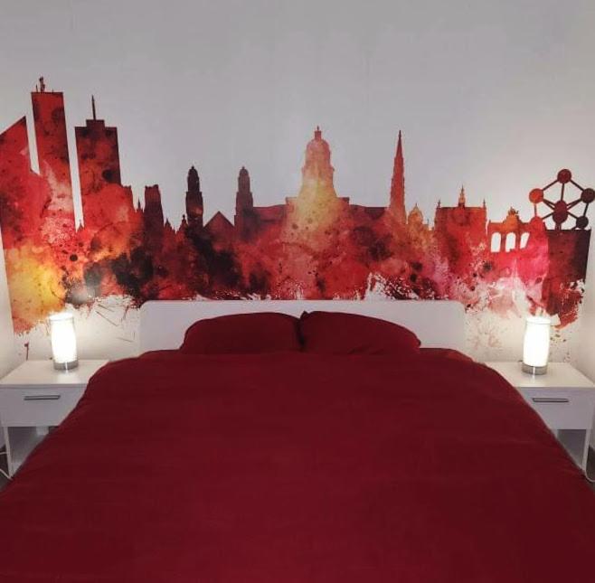 布鲁塞尔BRUSSELS EXPO APARTMENT的一间带红色床的卧室,享有城市天际线