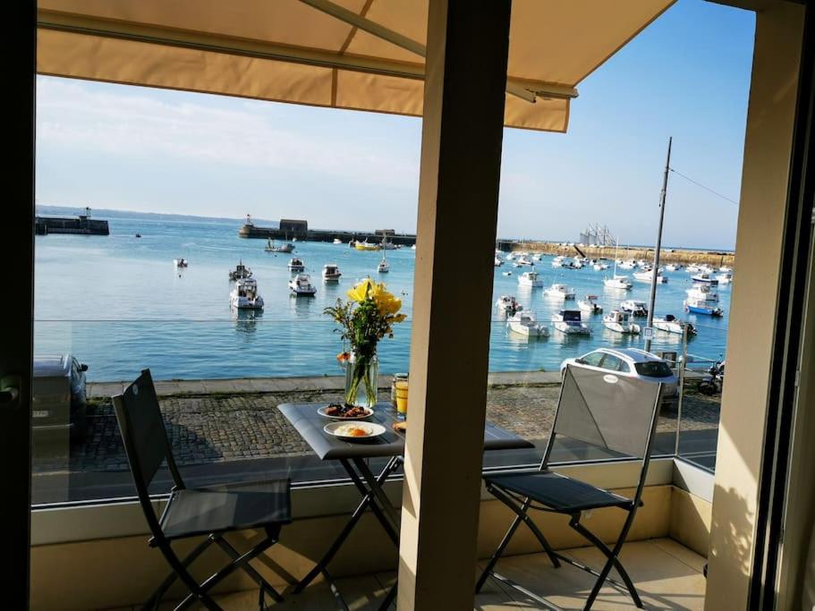 格朗维尔Charme et zénitude, avec vue exceptionnelle sur le port的阳台配有桌椅和船只。
