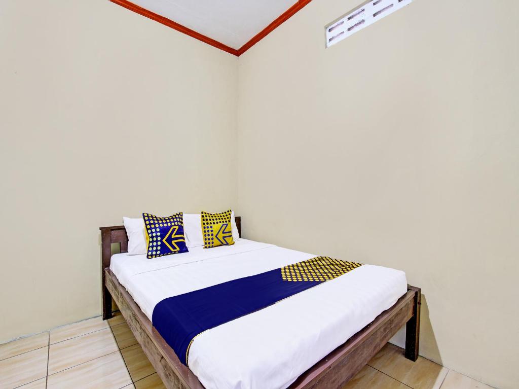 GlagahSPOT ON 92220 Sari Laut的一间卧室配有蓝色和黄色枕头的床