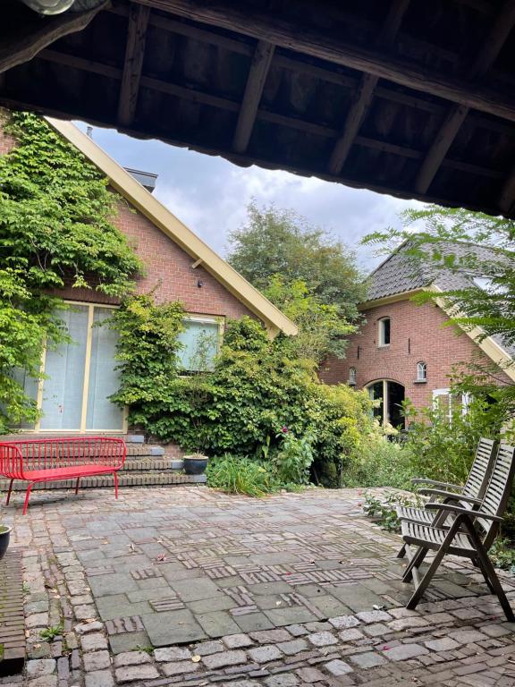 迪伦Heerlijke boerderij bij Veluwezoom in het Oude Dieren的两把长椅坐在大楼前的庭院里