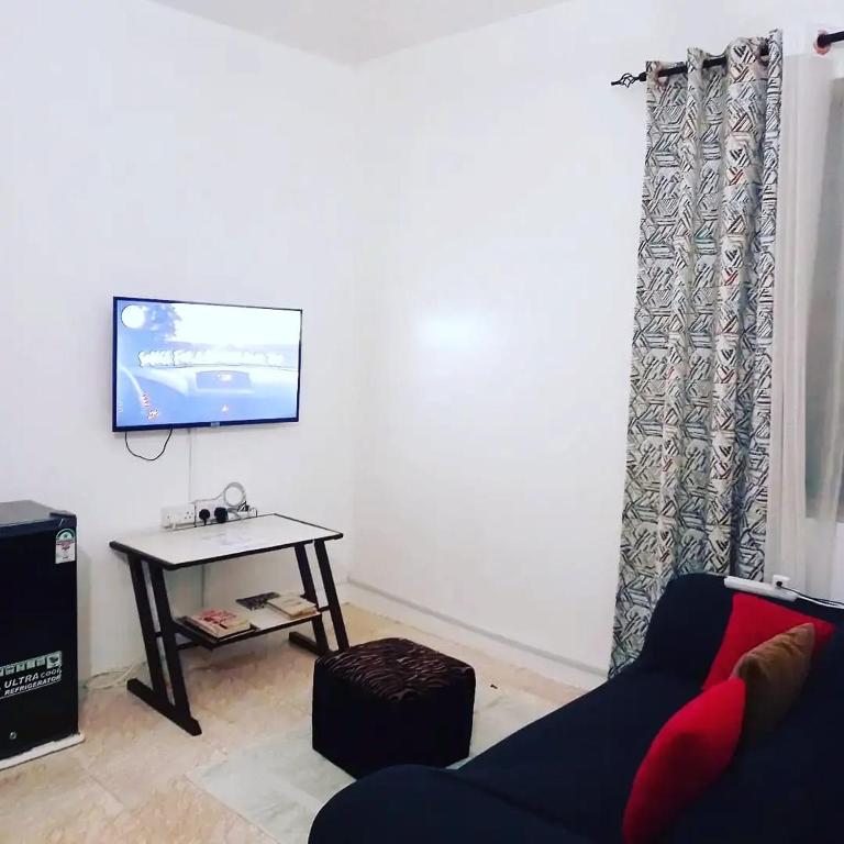 尼亚利Lux Suites Gichanga Studio Apartments的客厅配有沙发和墙上的电视