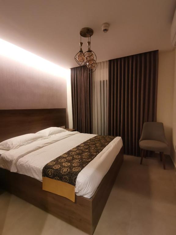 Umm UthainahDara apartment hotel的一间卧室配有一张床、一把椅子和一个吊灯。