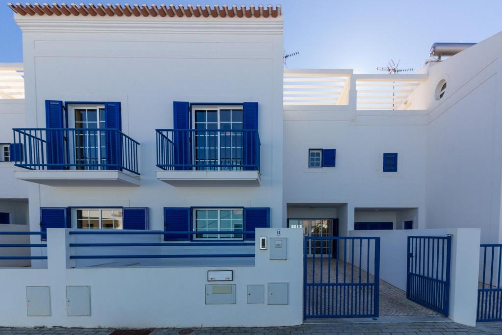 曼塔罗塔Blue Villa by ALGARVEMANTA的白色的建筑,设有蓝色的阳台和大门