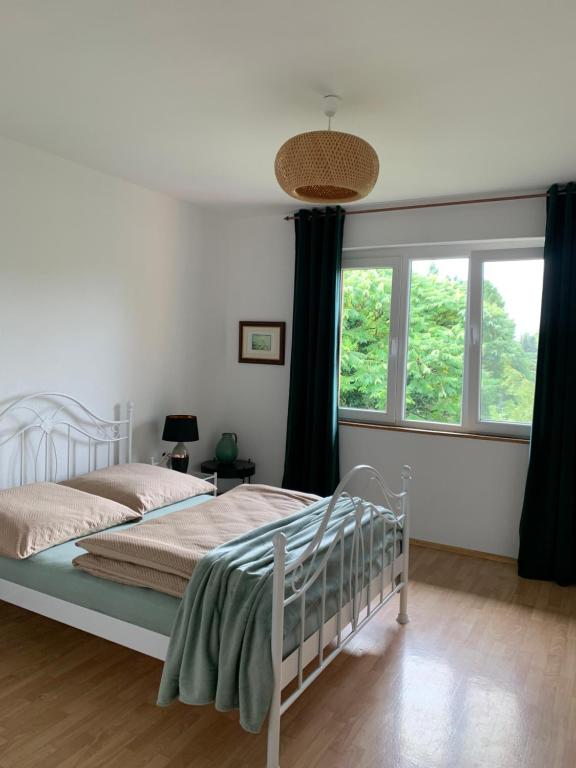 里拉辛根-沃布林根Apartament Blumenblick的卧室配有白色的床和窗户。