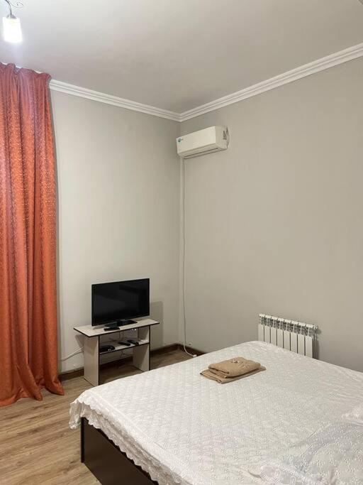 奇姆肯特Mondial apartments的一间卧室配有一张床和一张桌子上的电视