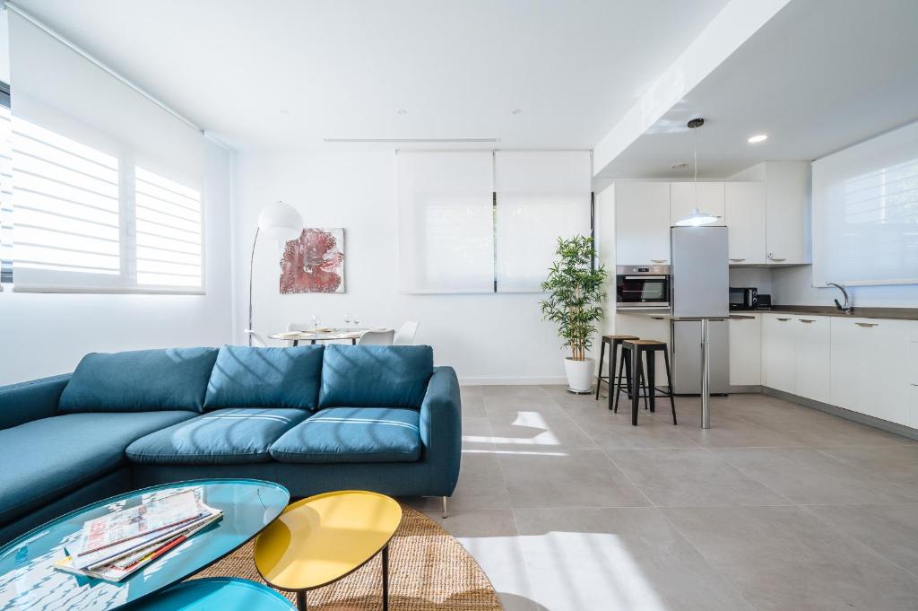 塞维利亚Apartmentos Marqués de Nervion的一间带蓝色沙发的客厅和一间厨房