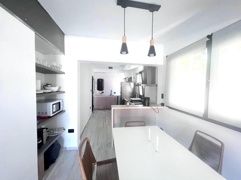 蒙特埃莫索Beach House Monte Hermoso的白色的厨房配有白色的柜台和椅子