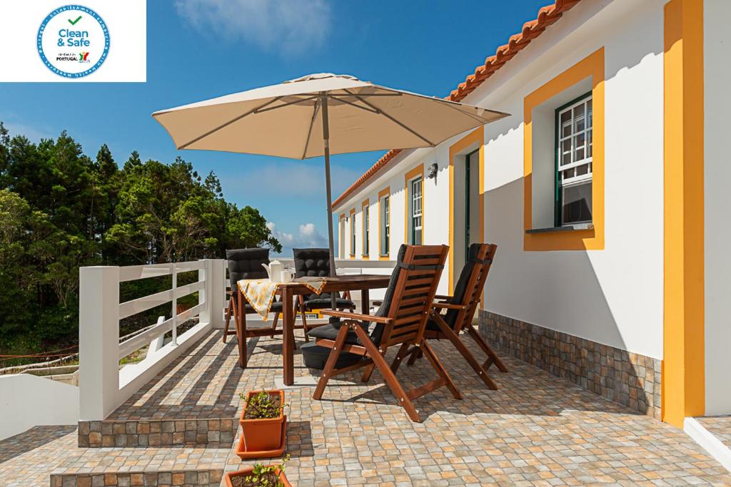 Calheta de NesquimCasa da Figueirinha的一个带桌子和遮阳伞的庭院
