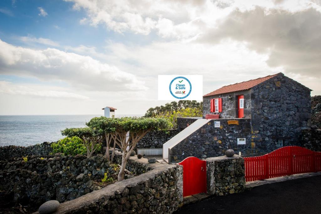 Calheta de Nesquim阿德加韦利亚度假屋的一座在海边设有红墙的建筑