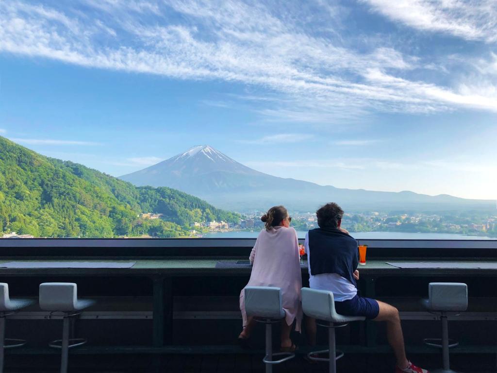 富士河口湖水之家酒店的两个人坐在椅子上,看着山