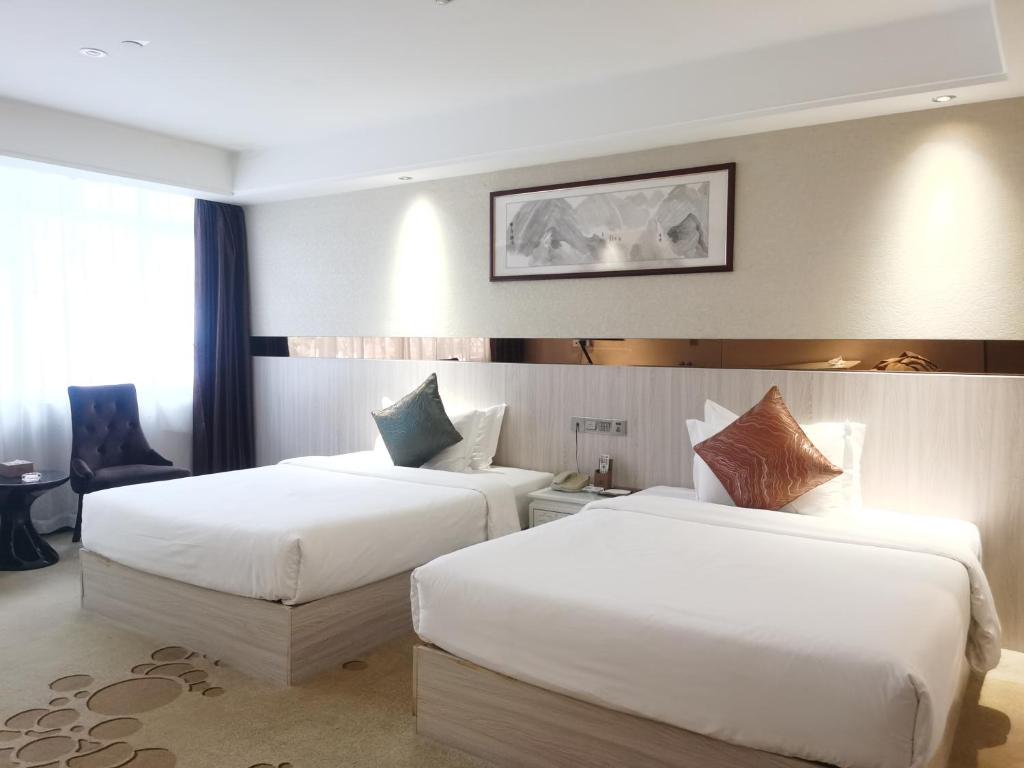 广州Paco Hotel Tianhe Coach Terminal Metro Guangzhou的配有白色床单的酒店客房内的两张床