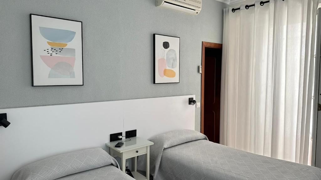 加的斯巴西亚旅馆的一间卧室设有两张床、一张桌子和一个窗口
