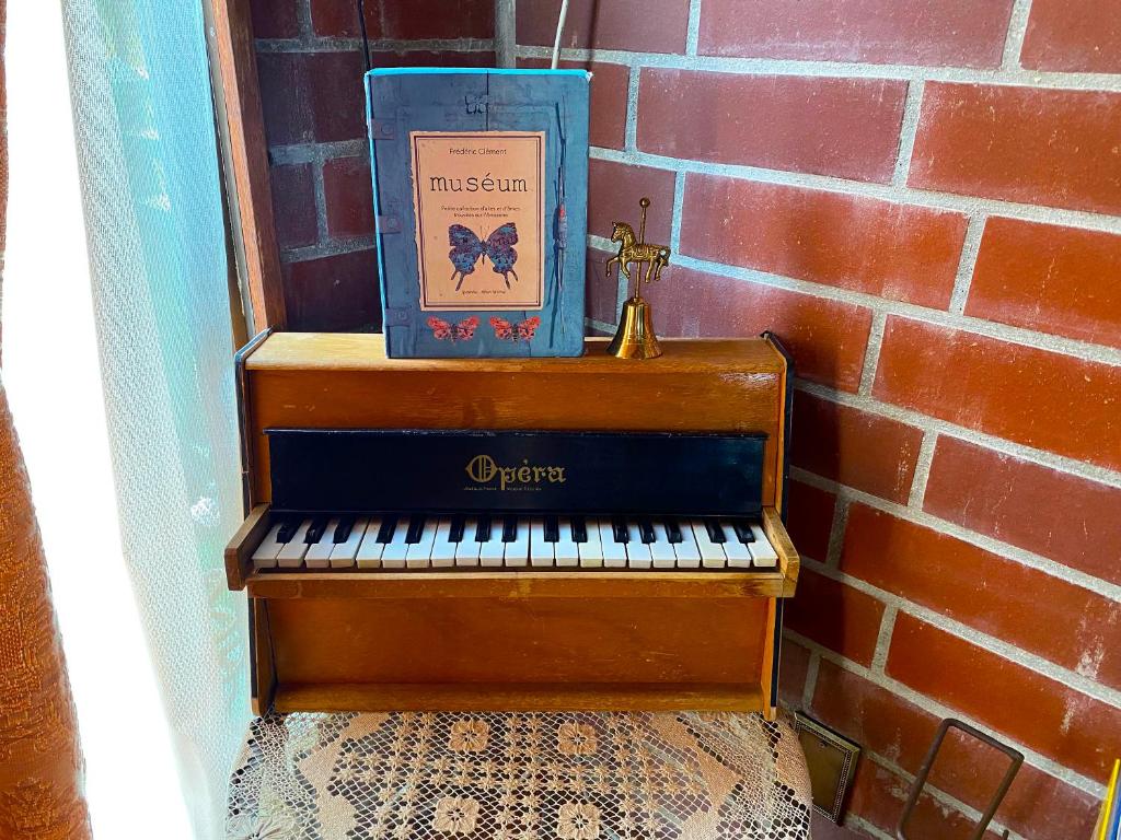 恩纳猫とピアノと星空のリゾートブティックコテージ - Starry Forest Cottage Okinawa -的坐在钢琴上砖墙旁的一本书