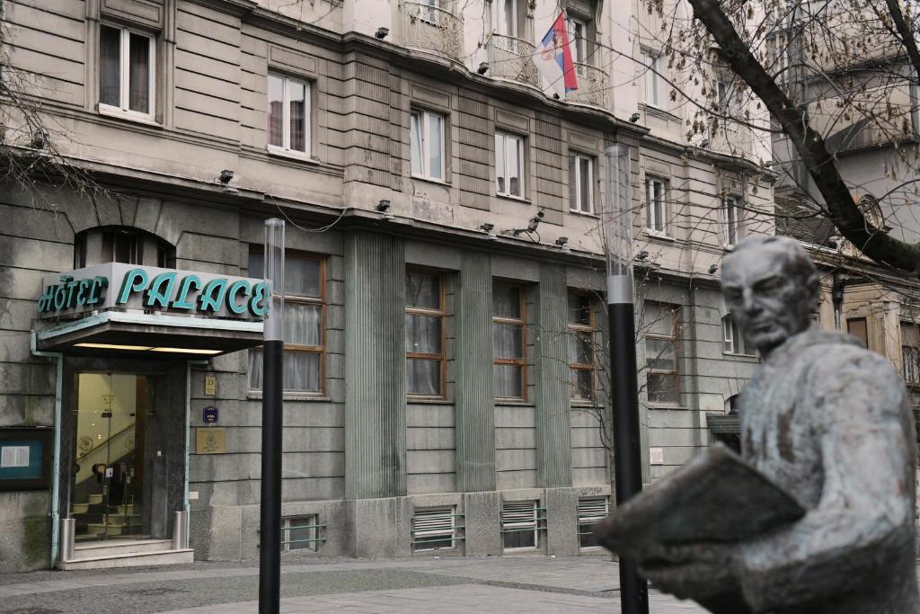 贝尔格莱德宫殿酒店 的站在建筑物前的一个人的雕像