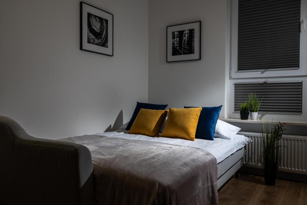 比亚韦斯托克ResiNest Apartamenty Kopernik的一间卧室配有黄色和蓝色枕头的床