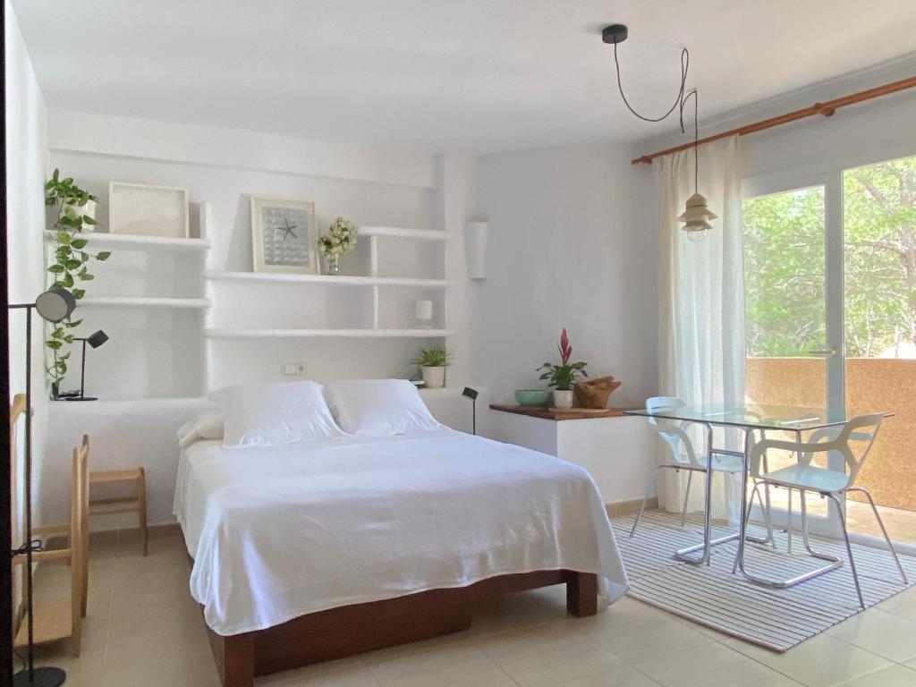 埃斯普霍斯CALMA Es Pujols的白色卧室配有床和玻璃桌