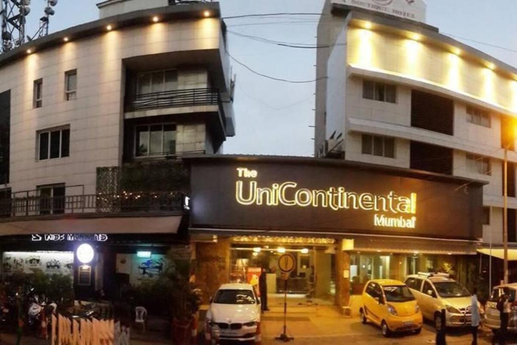 孟买Hotel Unicontinental的前面有汽车停放的建筑