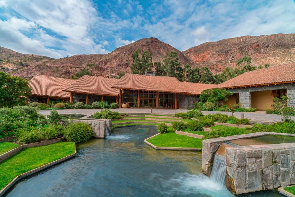 乌鲁班巴Tambo del Inka, a Luxury Collection Resort & Spa, Valle Sagrado的河中带瀑布的房子