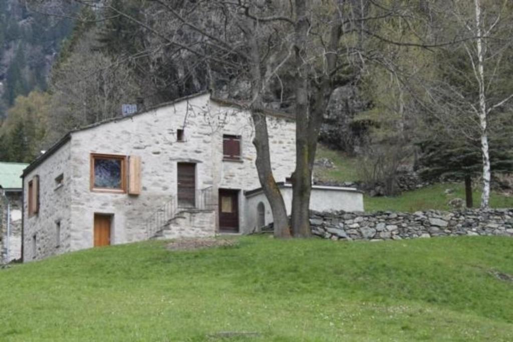 Maiensäss La Scera Val Poschiavo的绿色田野顶上的石头房子