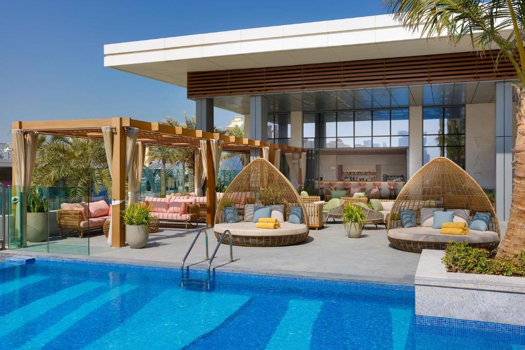 迪拜The St. Regis Dubai, The Palm的一个带藤床和椅子的游泳池的度假酒店