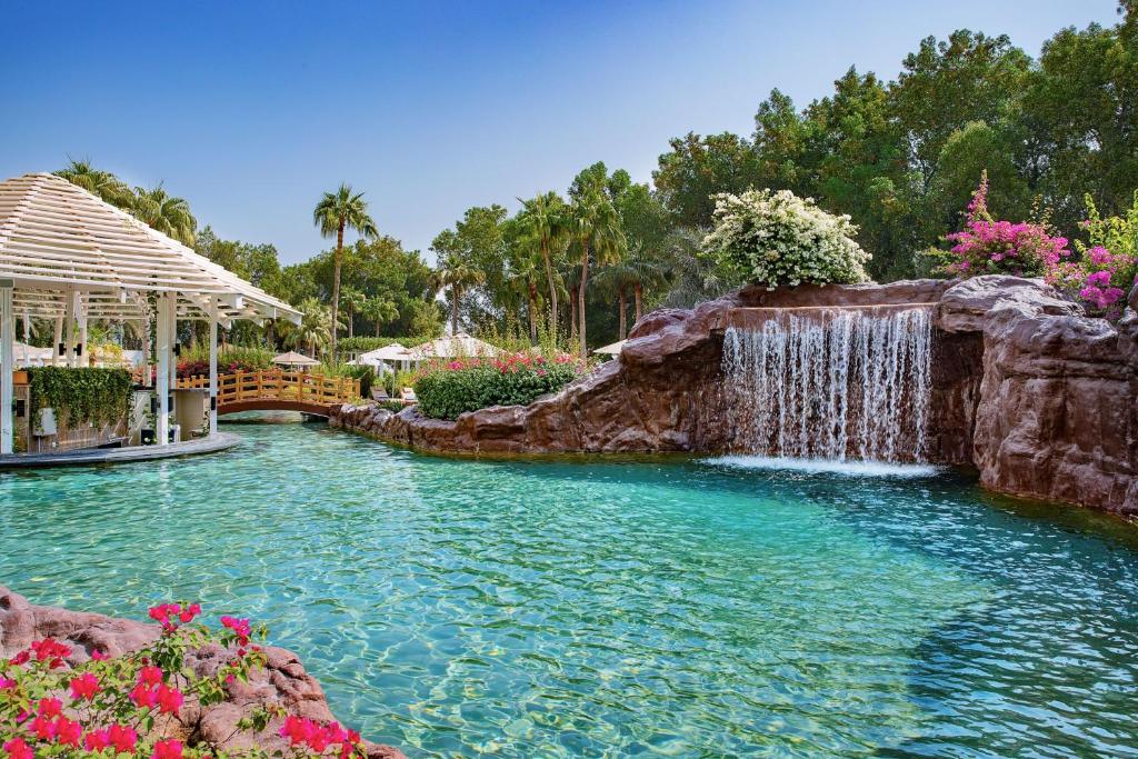 多哈多哈丽思卡尔顿酒店的鲜花庭院内带瀑布的游泳池