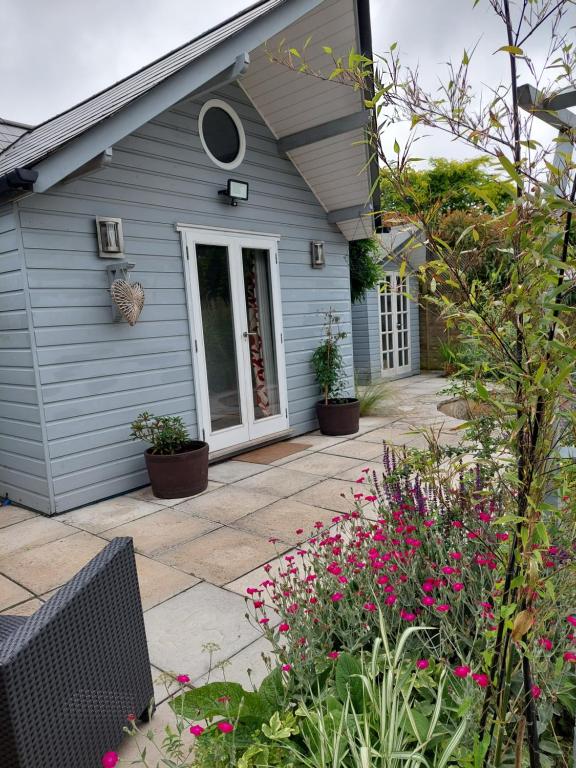 HoldenhurstPrivate Garden Lodge in Christchurch, Dorset for 4 - dogs welcome!的一座带庭院的房屋,前面有鲜花