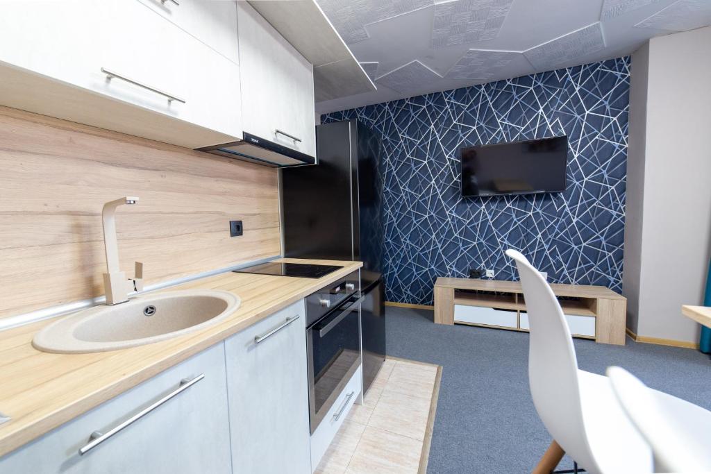 瓦尔纳Luxury Studio Apartment - Varna Residens的一个带水槽的厨房和墙上的电视