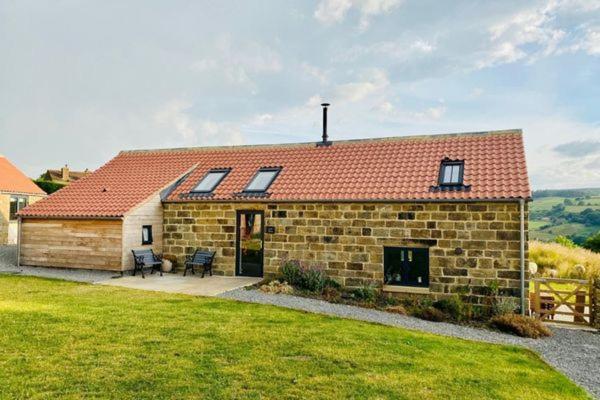 戈斯兰Green End Farm Cottages - The Cow Barn的红屋顶砖屋和院子