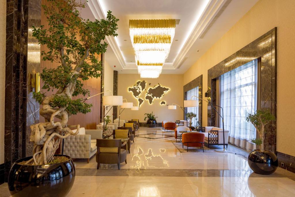 比什凯克Sheraton Bishkek的大厅,有长沙发和树的酒店