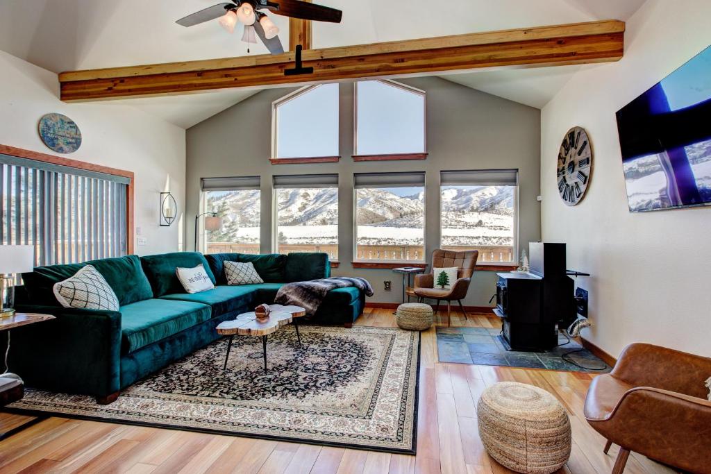 博伊西Twin Pines Cabin in Wilderness Ranch on Hwy 21, AMAZING Views, 20 ft ceilings, fully fenced yard, pet friendly, , Go paddle boarding at Lucky Peak, or snowshoeing in Idaho City and take in the hot springs, sleeps 10!的客厅设有绿色沙发和一些窗户。