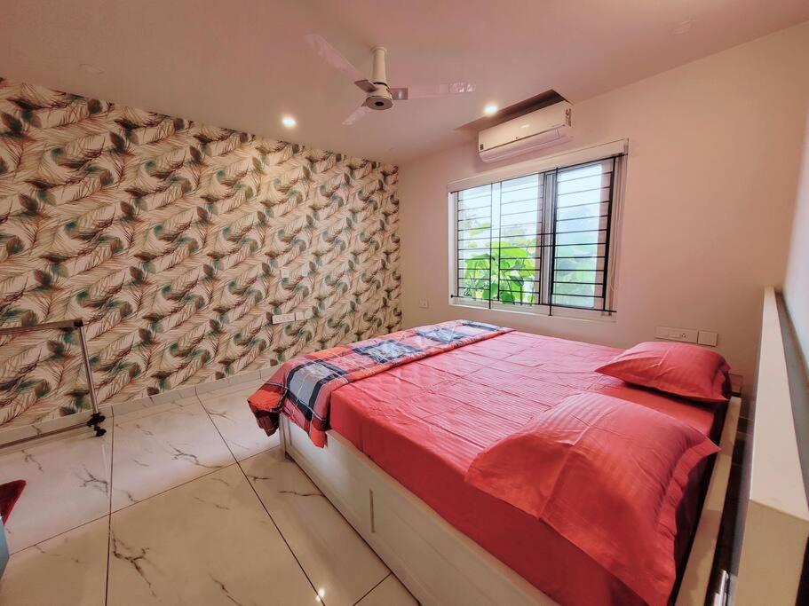 特里凡得琅Gangothri的一间卧室配有一张带红色床单的床和一扇窗户。