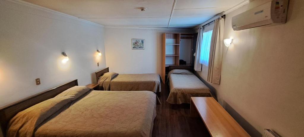 洛斯安第斯Hotel Los Andes的带三张床和窗户的客房