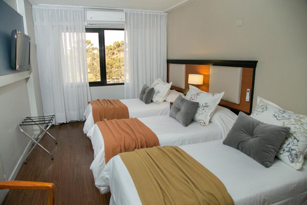 圣米格尔·德·图库玛Garden Park Hotel的酒店客房设有三张床和电视。