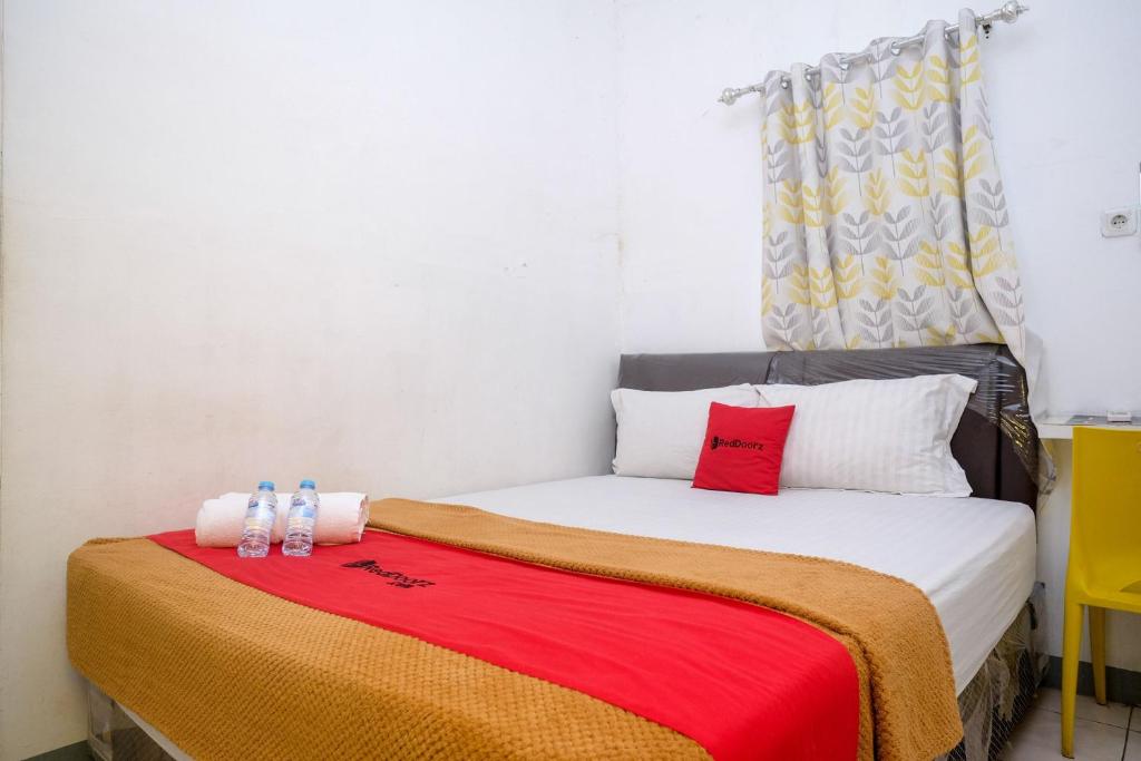 PanikiRedDoorz near Politeknik Manado的一间小卧室,配有一张带红色毯子的床