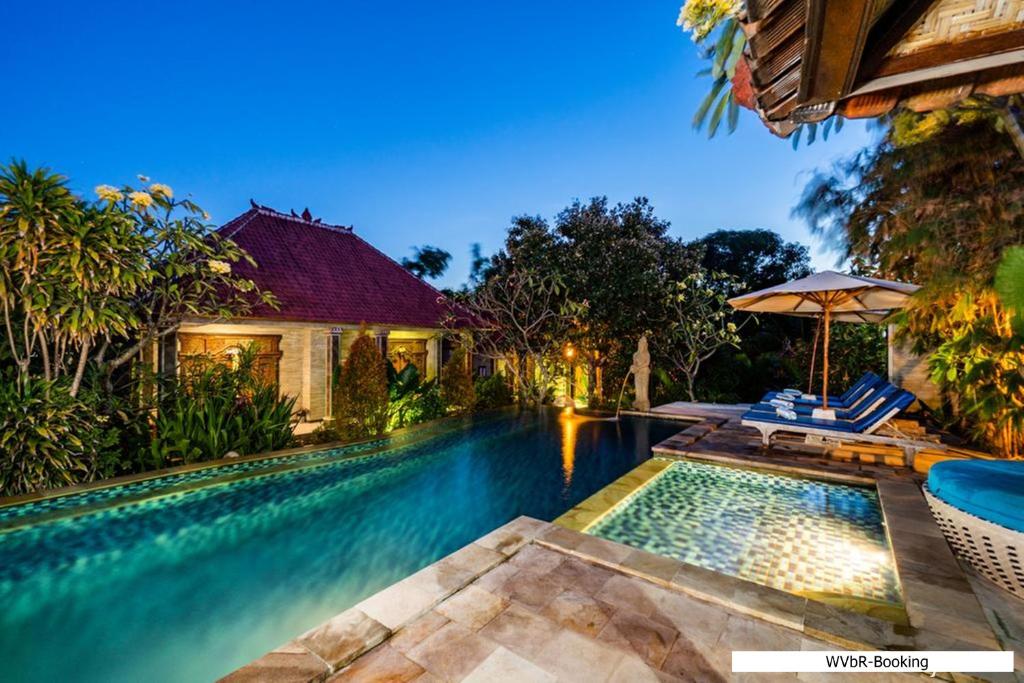 蓝梦岛Warisan Villa By Reccoma的房屋旁的游泳池配有椅子和遮阳伞