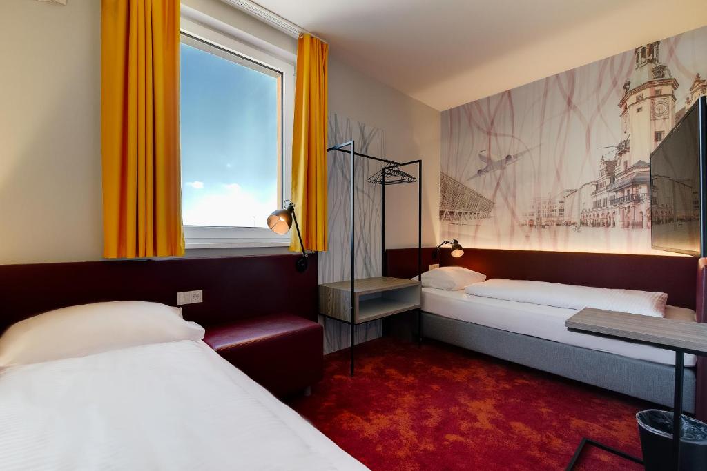 莱比锡Campanile Leipzig Halle Airport的酒店客房设有两张床和窗户。
