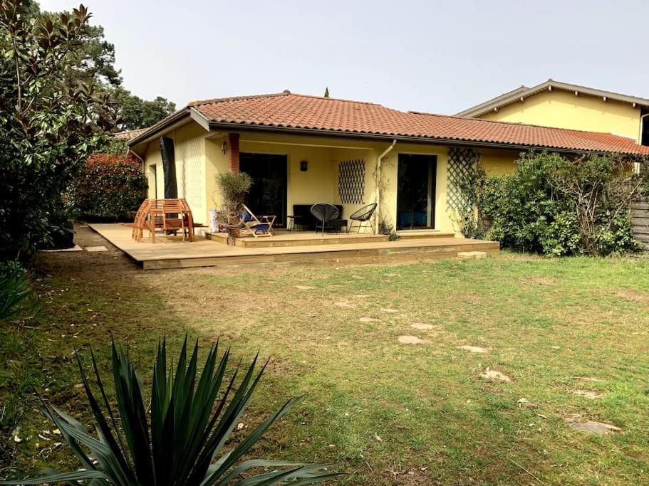 塞尼奥斯Villa Patio à 800 m de la plage的一座小黄色房子,在院子里有甲板