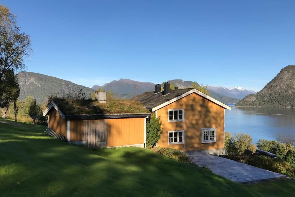 SæbøMoonvalley Lodge - stort & koselig hus - Måndalen的水体旁山丘上的房屋