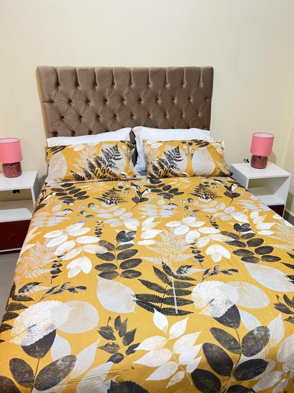 恩多拉Hibiscus Apartments的一张带黄色和白色被子和枕头的床