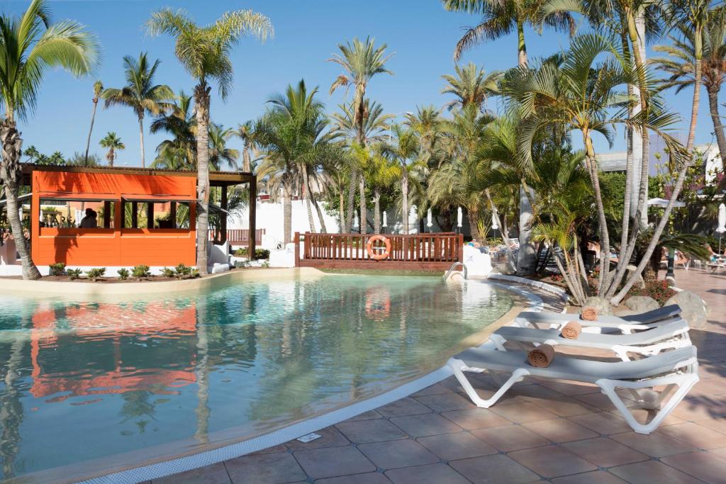 英格兰海滩Hotel Gran Canaria Princess - Adults Only的度假村的游泳池设有2把躺椅和棕榈树