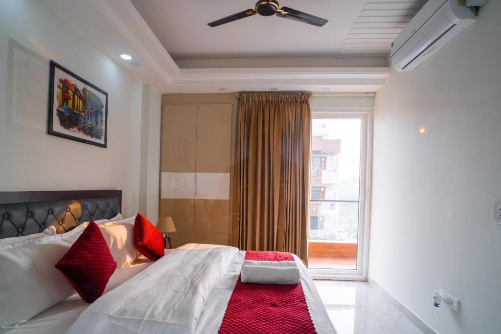 古尔冈The Lodgers 1 BHK Serviced Apartment Golf Course Road Gurgaon的一间卧室配有一张带红色枕头的床和一扇窗户