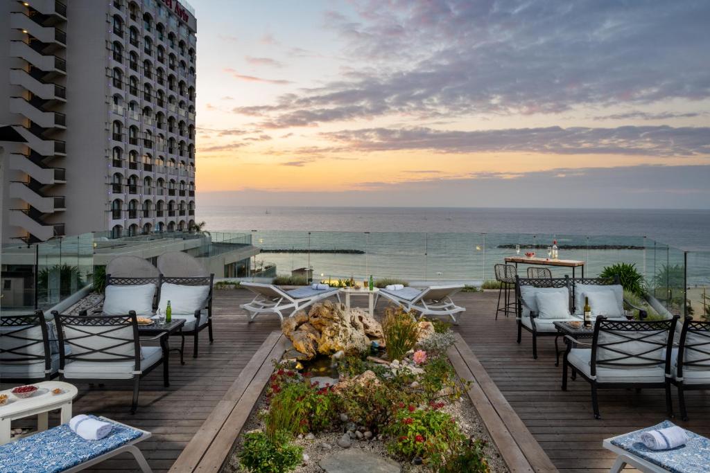 特拉维夫马克西姆3星级高级设计酒店的一个带桌椅的庭院和大海