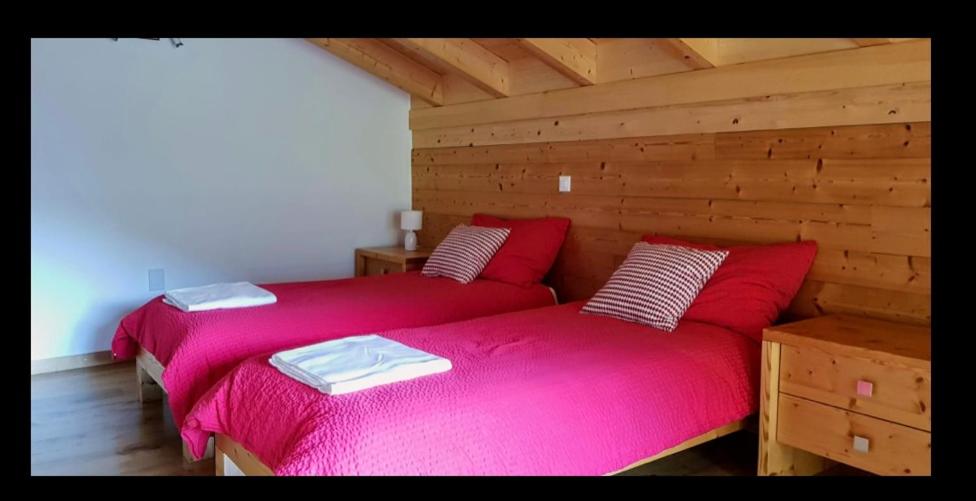 ChamosonRestaurant Les Vérines的木墙客房中的两张床和粉红色的床单