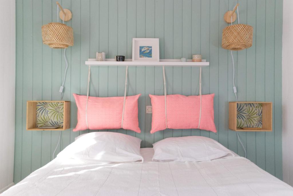 拉罗谢尔La Mariennée的卧室配有粉色和白色枕头,位于床上