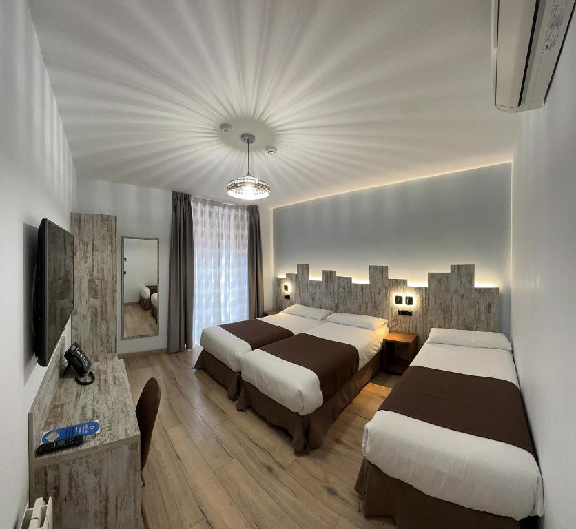 马德里Hostal Anton Martin的酒店客房设有两张床和电视。