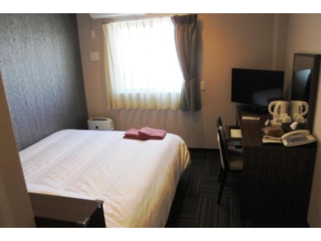 IchiharaBusiness Hotel Goi Onsen - Vacation STAY 78235v的配有一张床、一张书桌和一扇窗户的酒店客房