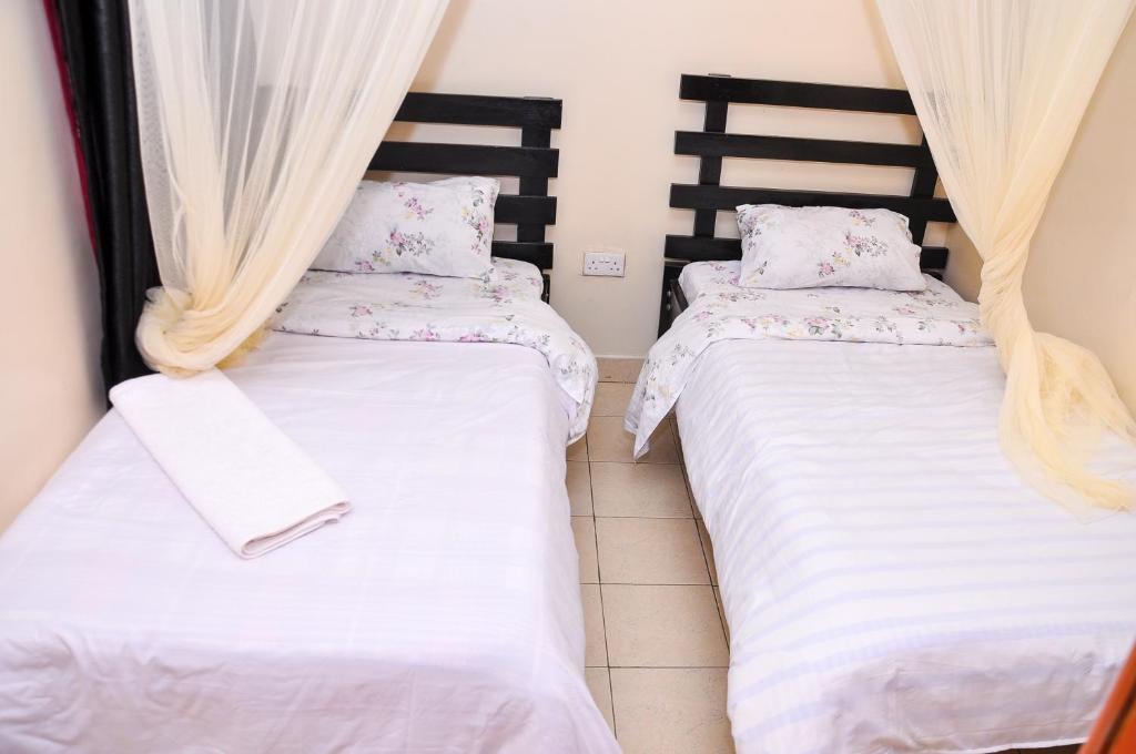 内罗毕Milany Homes - NEAR JKIA AIRPORT的配有白色床单的客房内的两张床